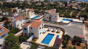 Een resort met meerdere zwembaden, uitzicht op het strand en een mediterrane bouwstijl.