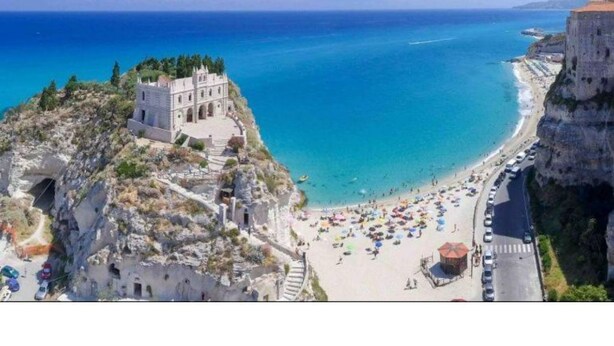 Ein Küstenblick mit einem historischen Gebäude, das auf einen Strand blickt.