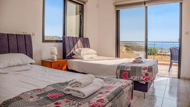 Ein Hotelzimmer mit zwei Betten, einem Balkon mit Blick und einem großen Fenster.