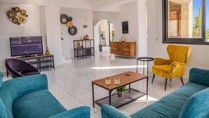 Ein modernes Wohnzimmer mit türkisfarbenen Sofas, einem gelben Sessel, einem Couchtisch und einem Fernseher auf einem Lowboard.