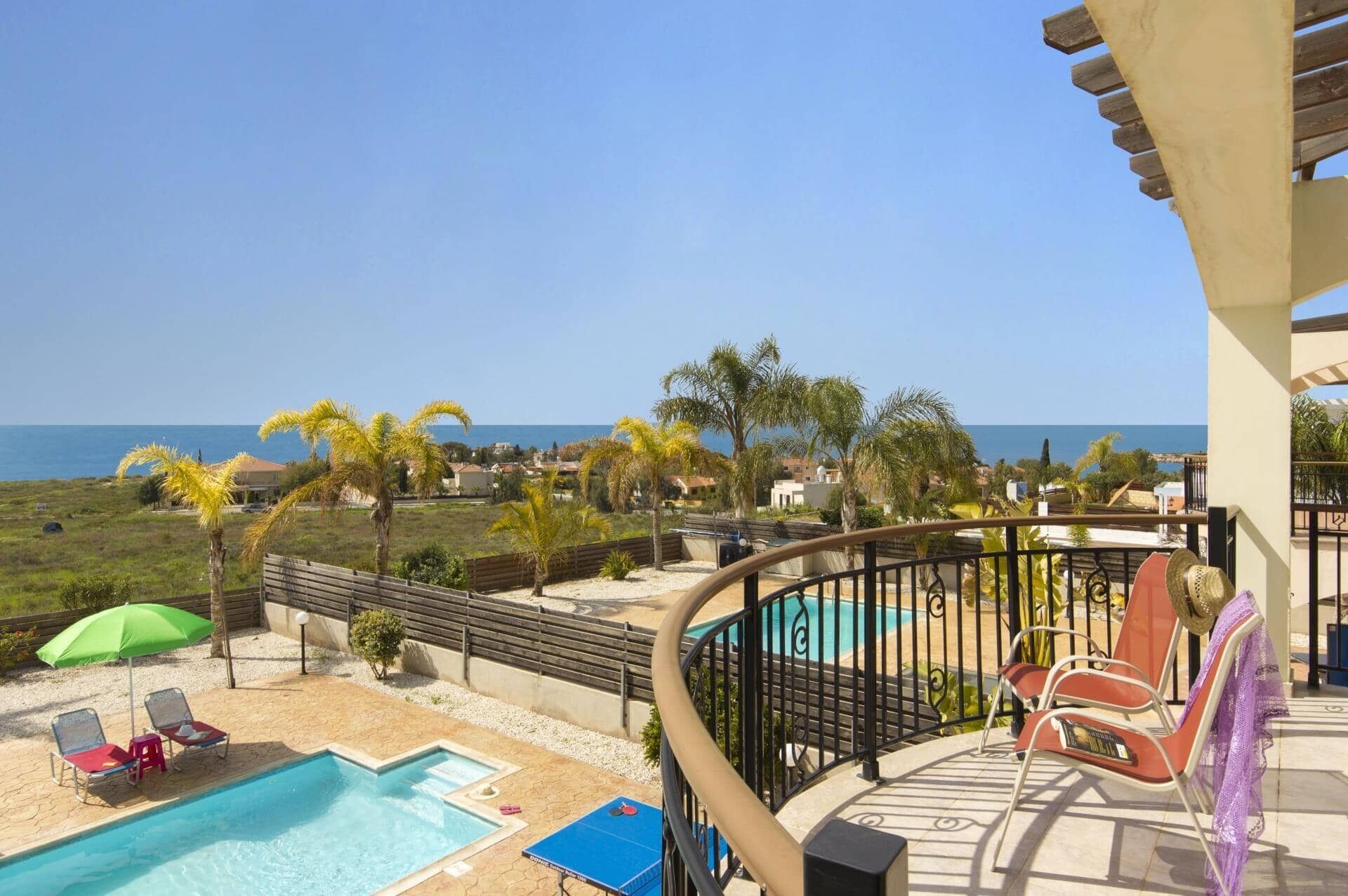 A pool area with lounge chairs and a view of the sea.