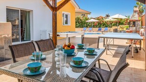 An outdoor dining area with a pool in the background. - Villa Frida by Villa Plus (Peyia)