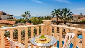 A balcony with a round table, chairs, and a bowl of fruit. - Villa Frida by Villa Plus (Peyia)