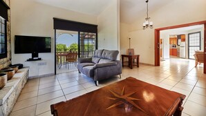 A spacious living room with a flat-screen TV, a grey sofa, and a wooden coffee table with a star design. - Villa Theo Sapphire by Villa Plus (Latchi)