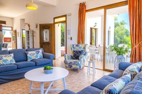 A modern living room with a blue sofa set, a patterned armchair, and a small white table with a plant.