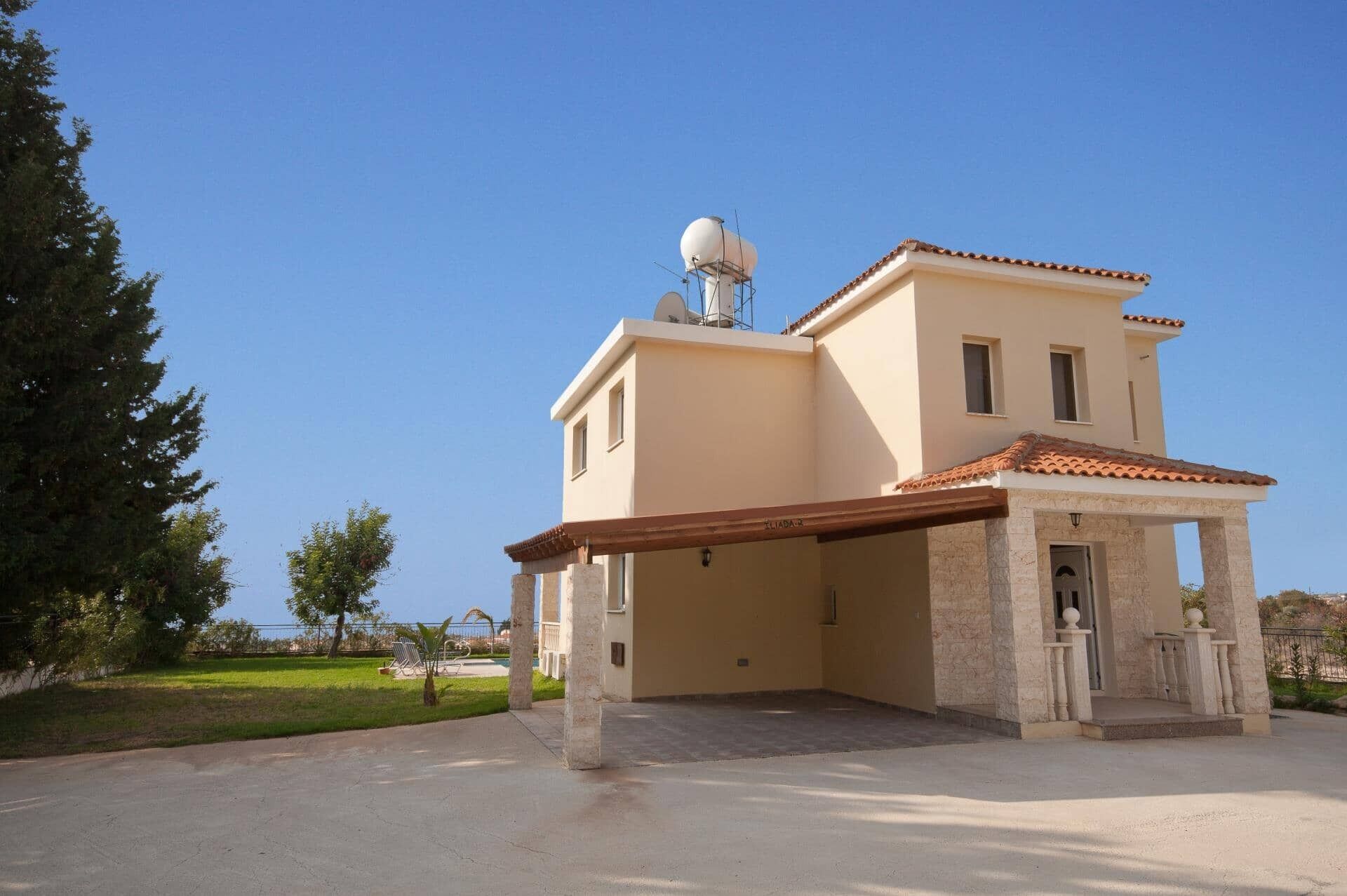 A two-story building with a covered entrance, a satellite dish, and a small garden area.