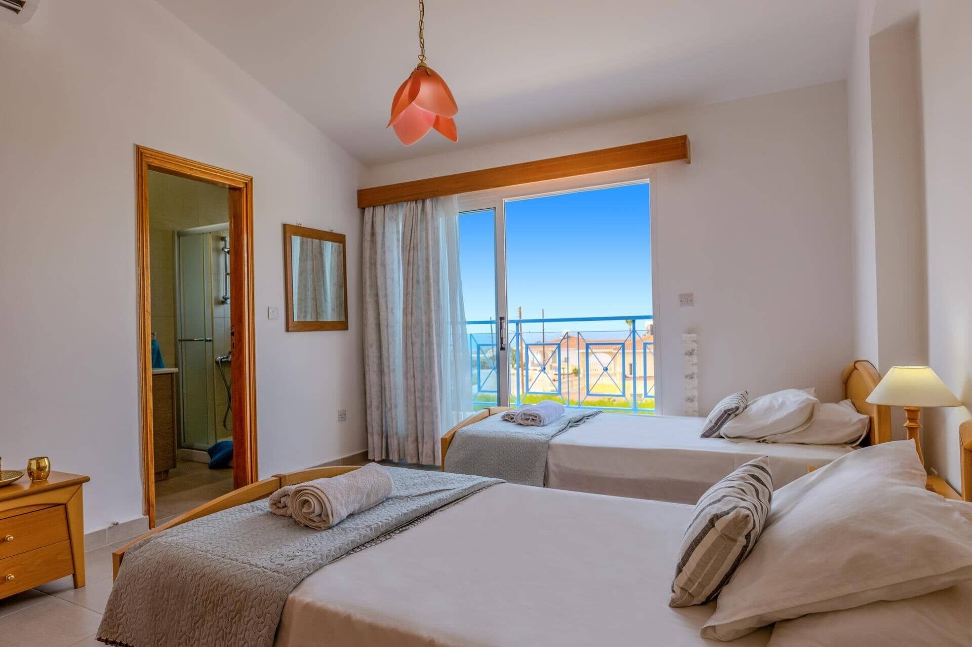 Ein Hotelzimmer mit zwei Betten, einem Badezimmer und einem Balkon mit Blick.
