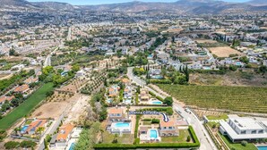 An aerial view of a residential area with a large house featuring a swimming pool, a tennis court, and a well-maintained garden. - Villa Joanna Coral Bay by Villa Plus (Peyia)