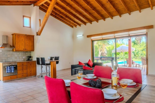 A dining area with red chairs, a table set for two, and a view of the outdoors through a glass door.