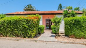 Um edifício com telhado em telhas, uma porta e um caminho que o leva até ele.