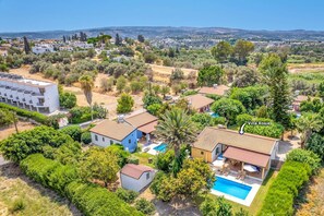 A villa with a swimming pool, surrounded by lush greenery and a view of a distant town. - Villa Rosie by Villa Plus (Poli Crysochous)