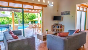 Uma sala de estar ampla com piscina, assentos confortáveis e televisão.