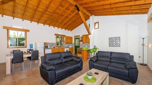 A spacious living area with two black sofas, a wooden coffee table, and a kitchen in the background. - Villa Iriss by Villa Plus (Poli Crysochous)