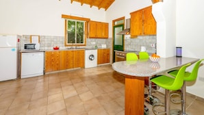 A compact kitchen with wooden cabinets, a washing machine, a microwave, and a sink. - Villa Iriss by Villa Plus (Poli Crysochous)