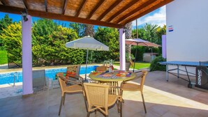 Un patio al aire libre con piscina, muebles de mimbre y una mesa con mantel.
