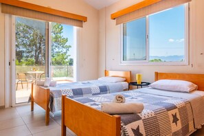 A hotel room with two beds, a balcony, and a view of the sea.