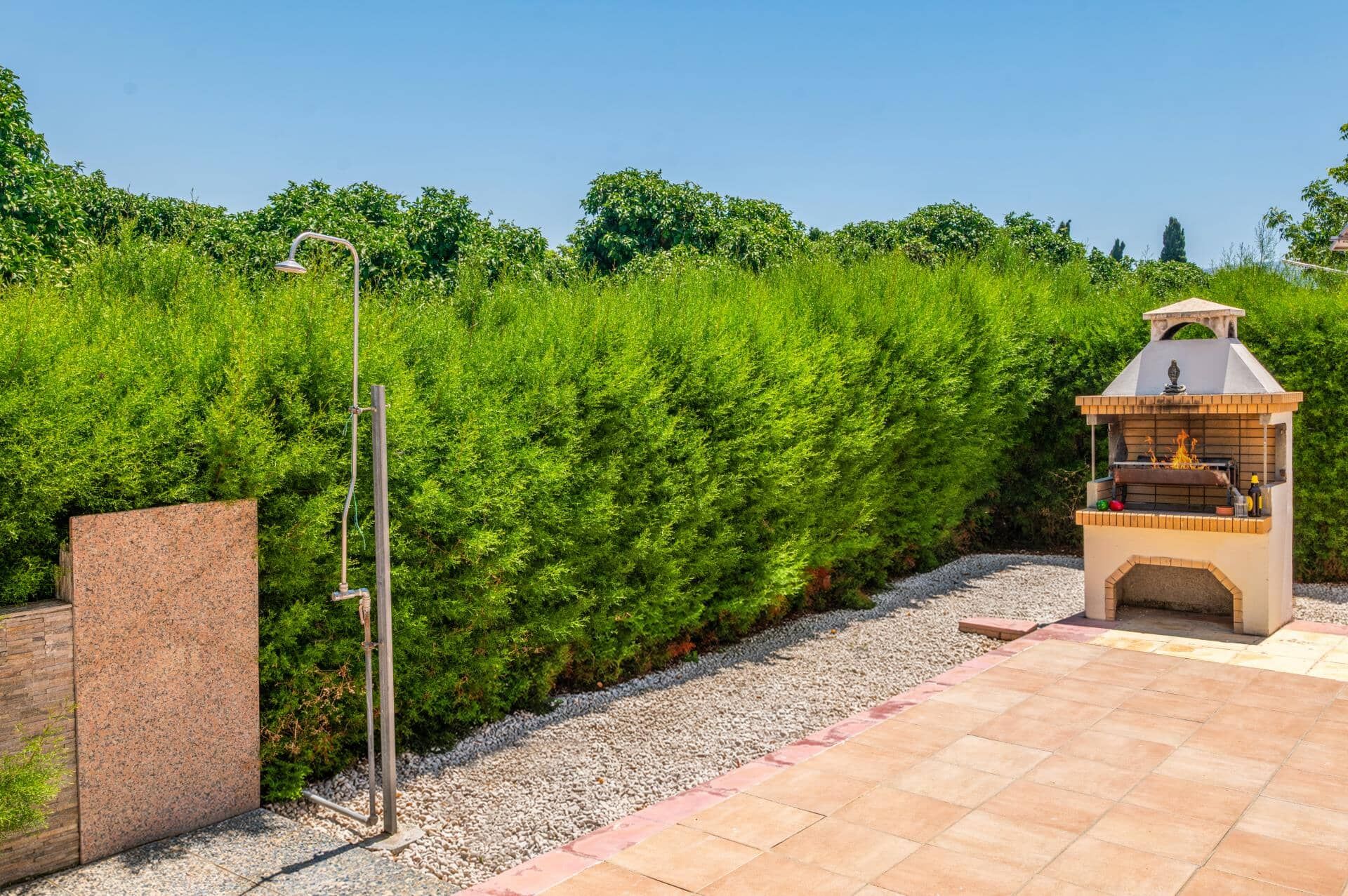 Un patio con una parrilla incorporada y un cabezal de ducha de metal.