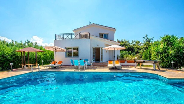 Ein modernes, zweistöckiges Haus mit Swimmingpool, Außenbereich und üppiger Bepflanzung.