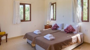 Ein Doppelbett mit zwei Kissen, ein Nachttisch mit Lampe und ein Fenster mit Vorhängen.