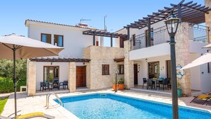 Um edifício de dois andares com piscina, área de estar externa e pérgola.
