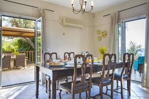 A dining area with a long table, dark wooden chairs, and a chandelier.