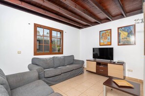 A living room with a grey sofa, a TV, a wooden cabinet, and two framed artworks on the wall. - Villa Siroco Lanzarote by Villa Plus (Playa Blanca)