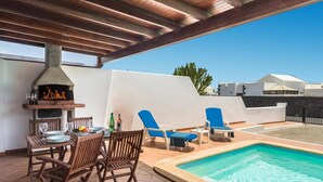 Un espacio al aire libre cubierto con piscina, una parrilla y zona de estar.