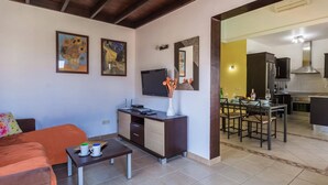 Una sala de estar con sofá, mesa de centro, televisor y obras de arte en la pared.