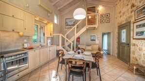 A spacious kitchen with a dining area, wooden beams, and a staircase leading to an upper level.