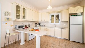 Una cocina con armarios blancos, una isla central, lavadora y refrigerador.