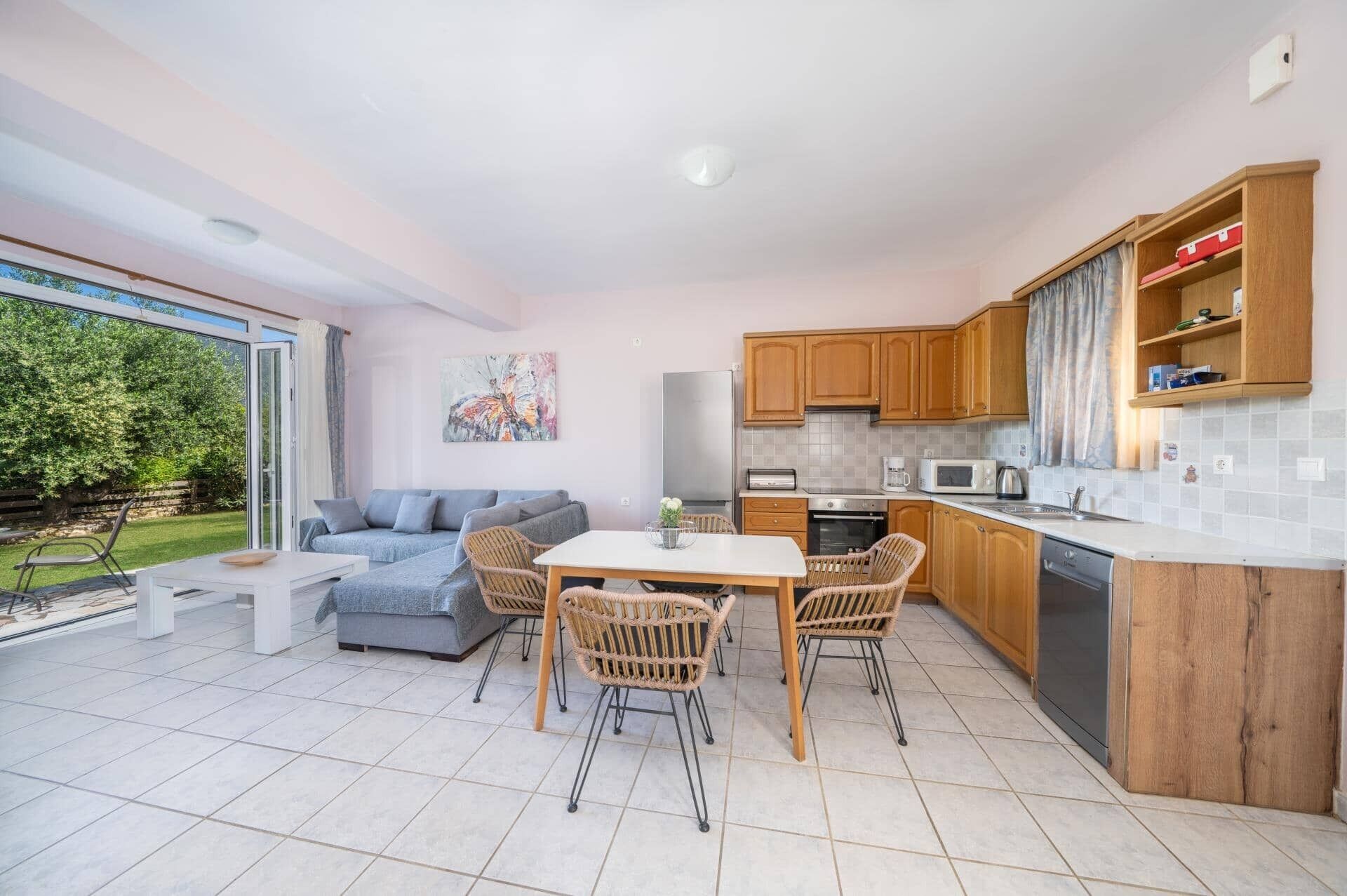 Una cocina moderna con armarios de madera, un comedor con mesa y sillas, y una sala de estar con sofá y un cuadro.