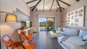 A modern living room with a TV, seating, and artwork. - Villa Nectar by Villa Plus (Cephalonia)