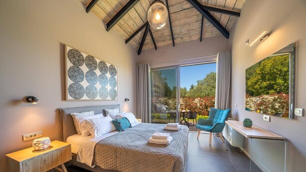 A bedroom with a bed, bedside table, and a view of the outdoors. - Villa Nectar by Villa Plus (Cephalonia)