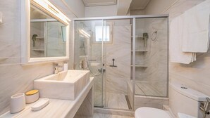 Un baño moderno con ducha de vidrio, lavamanos de mármol y un inodoro.