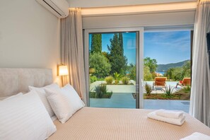 Une chambre d’hôtel avec un lit, une table de chevet, une lampe et une vue sur une piscine et un jardin.