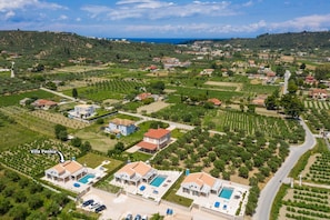 Vue aérienne d’un quartier résidentiel avec des villas, dont la villa Peonia, qui dispose de piscines et d’un aménagement paysager bien entretenu.