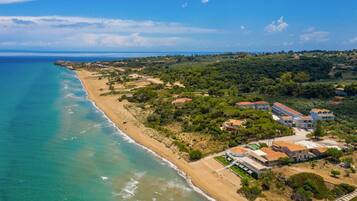 Une vue aérienne d’une zone côtière avec une plage, des bâtiments et de la végétation.