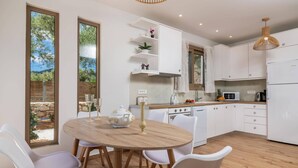 A modern kitchen with white cabinets, a round wooden table, and white chairs.