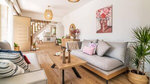 A modern living room with a sofa, a coffee table, and a staircase leading to a kitchen.