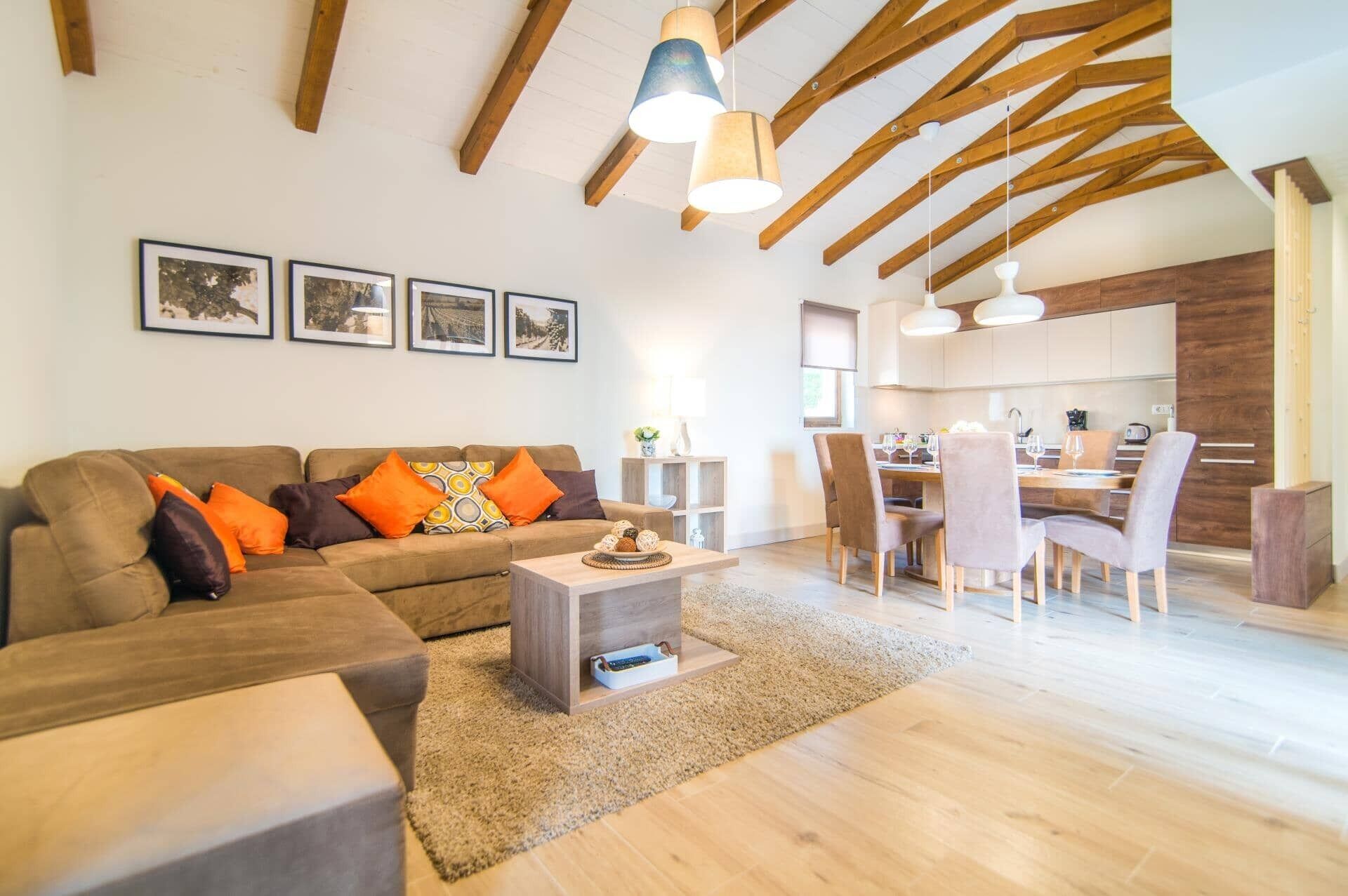 A modern living room with a sofa, coffee table, and a dining area with chairs and a table.