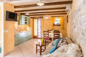A cozy living area with a sofa, a dining table, and a kitchen area with cabinets and a TV.