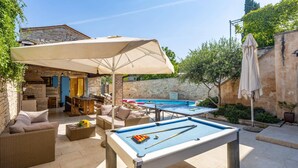 An outdoor pool area with a pool table, lounge chairs, and a covered seating area. - Villa Fumica by Villa Plus (Radetići)