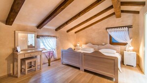 A bedroom with a wooden ceiling, a bed, a bedside table, a nightstand, a mirror, and a window with curtains. - Villa Fumica by Villa Plus (Radetići)