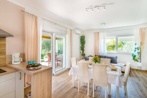 A modern kitchen with a coffee maker, dining area with white chairs, and a view of the outdoors. - Villa Ladonja by Villa Plus (Pula)