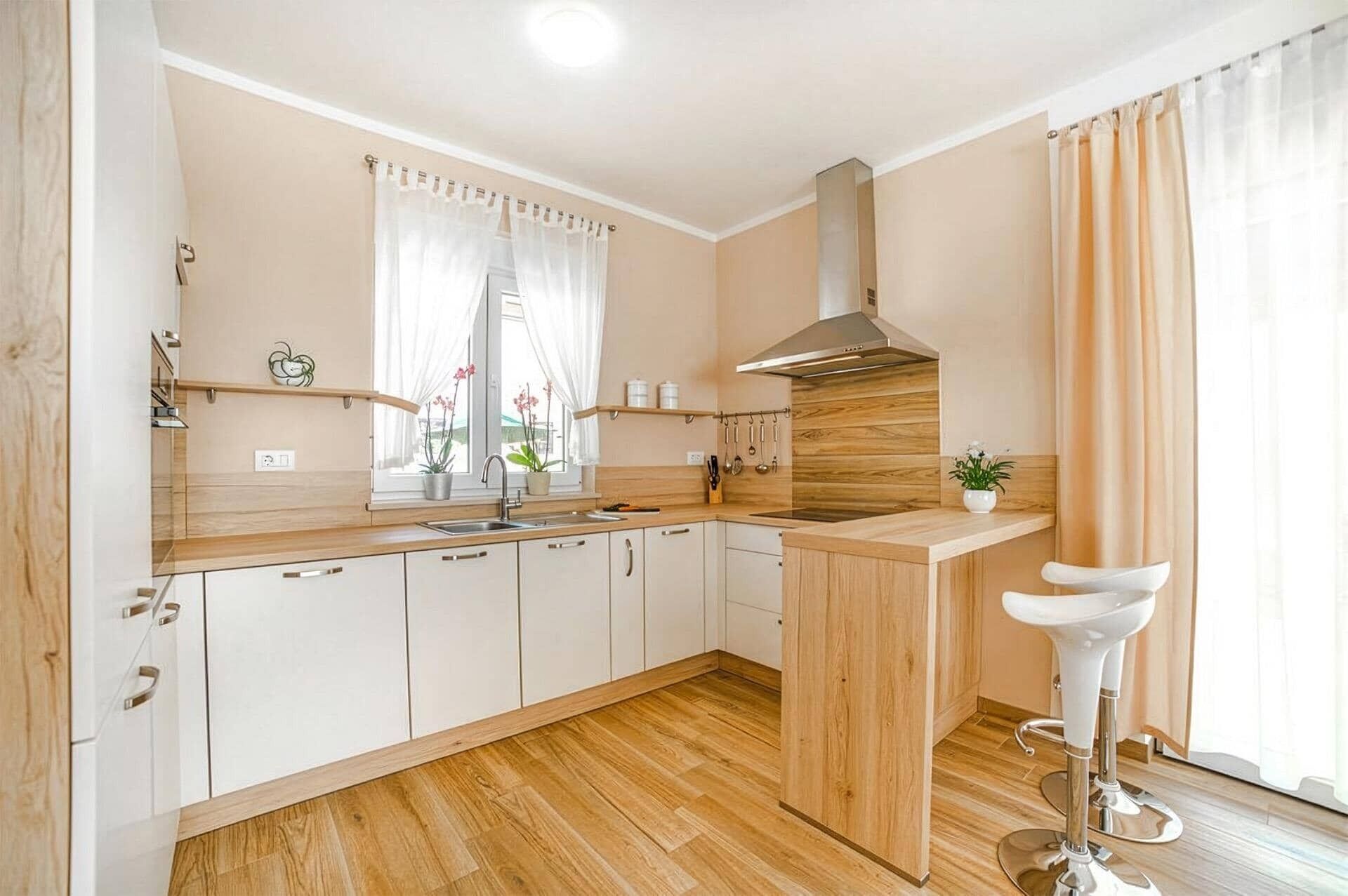 Una cocina moderna con armarios de madera, un lavamanos de acero inoxidable y una estufa integrada.