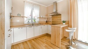A modern kitchen with wooden cabinets, a stainless steel sink, and a built-in stove. - Villa Ladonja by Villa Plus (Pula)