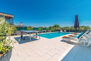 A pool area with a table tennis table, lounge chairs, and umbrellas. - Villa Florentina by Villa Plus (Stokovci)