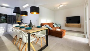 A modern kitchen with a dining area, a sofa, and a TV in a living room. - Villa Lavandula by Villa Plus (Stokovci)