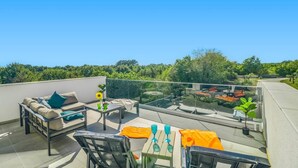 A rooftop terrace with a sofa, chairs, and a table, overlooking a lush green landscape. - Villa Lavandula by Villa Plus (Stokovci)