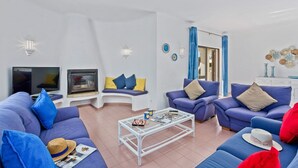 Ein Wohnzimmer mit zwei Sofas, einem Couchtisch, einem Fernseher und einem Kamin.